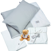 Bedding set in light grey with white flat sheet and baby blanket. Small teddy bear.