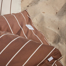 Brown jersey bedding with stripes, on a sandy beach